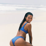 Girl in a blue bikini playing in the sand