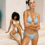 Two women in swimsuits standing on a staircase with a neutral background