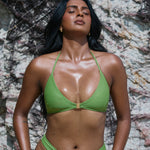 Woman wearing a green bikini standing against a rocky background