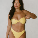 Woman wearing a yellow bikini against a plain background
