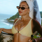 Woman in a yellow bikini holding a bottle of champagne with a scenic background