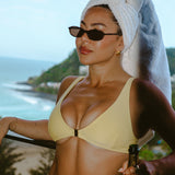 Woman in a yellow bikini holding a bottle of champagne with a scenic background